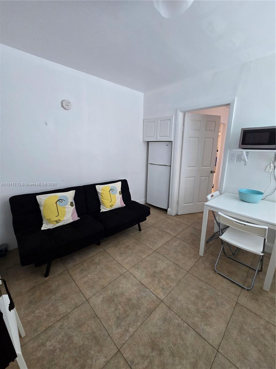 445 Northwest 125th Street, Unit 2 North Miami, FL 33168 - Photo 5 of 10 a living room with a bed and a table