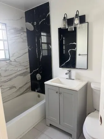 a bathroom with a sink and mirror with bathtub