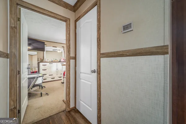 a view of a hallway with wooden floor and a bathroom