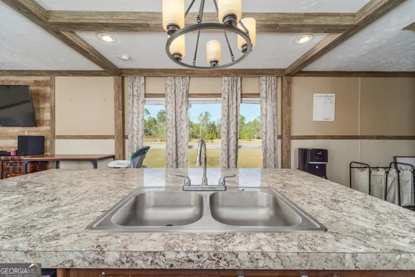 a view of kitchen with granite countertop a large window and a sink