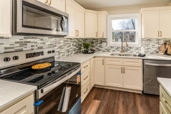 a kitchen with cabinets appliances and a wooden floor