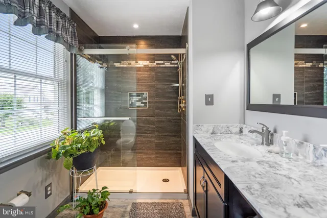a bathroom with a granite countertop sink a toilet and shower
