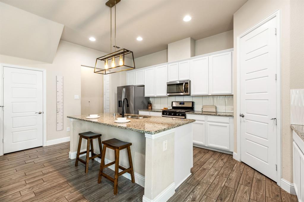 620 Ansley Way Allen, TX 75013 - Photo 12 of 31 a kitchen with stainless steel appliances a microwave a stove a sink dishwasher a refrigerator white cabinets and wooden floor