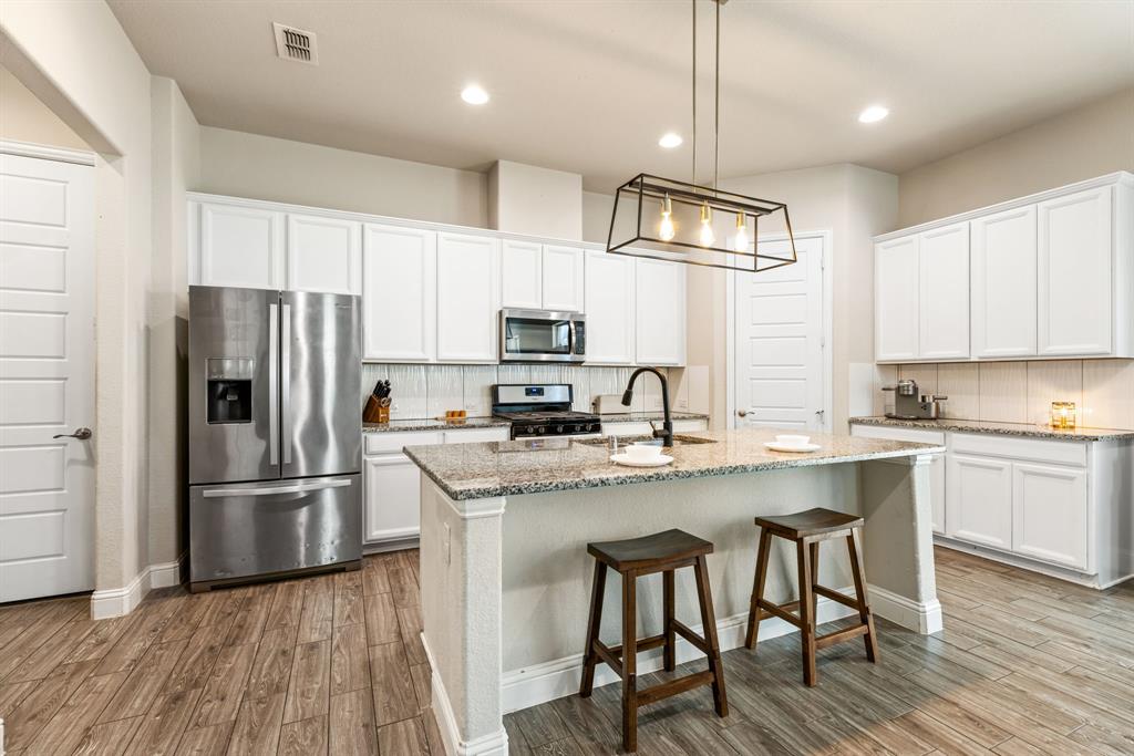 620 Ansley Way Allen, TX 75013 - Photo 13 of 31 a kitchen with stainless steel appliances granite countertop a refrigerator a stove top oven a sink dishwasher and a refrigerator with wooden floor