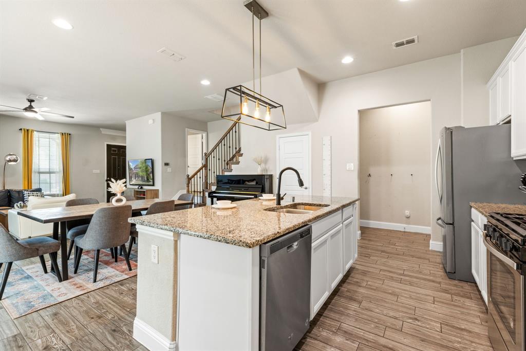 620 Ansley Way Allen, TX 75013 - Photo 15 of 31 a large kitchen with stainless steel appliances kitchen island a table chairs in it and wooden floors