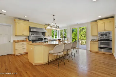 a kitchen with stainless steel appliances a stove a sink a center island and wooden floor