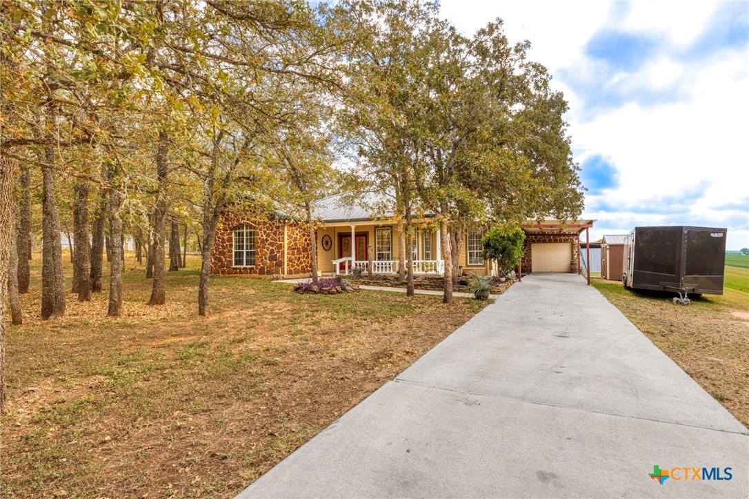a view of a yard with a house and trees in the background
