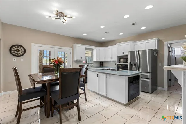 a kitchen with stainless steel appliances kitchen island granite countertop a dining table chairs and microwave