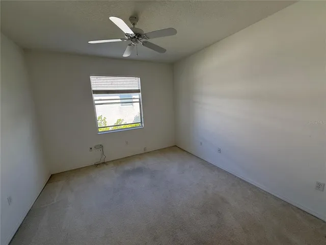 an empty room with a window and a fan