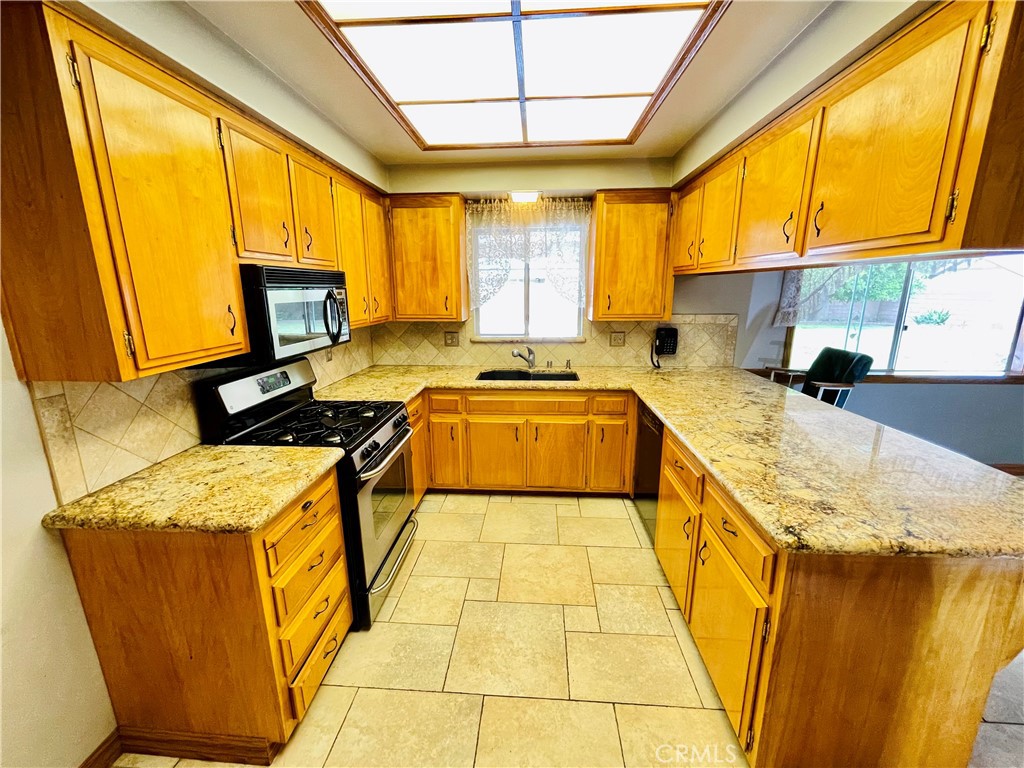 5875 Olive Avenue Rialto, CA 92377 - Photo 26 of 54 a kitchen with stainless steel appliances granite countertop a sink a stove and a microwave