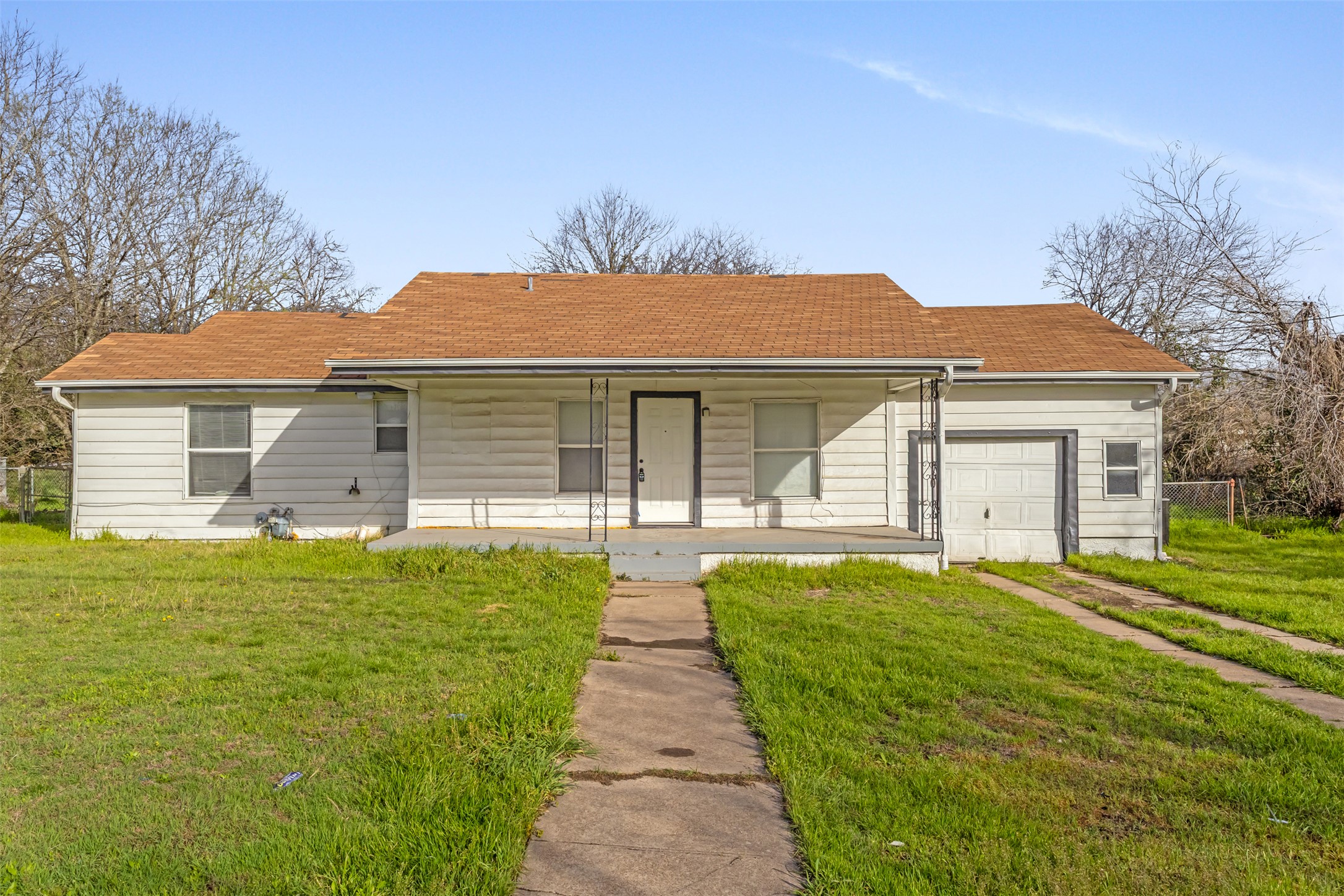 Single story home with a porch, a front yard, roof with shingles, driveway, and an attached garage