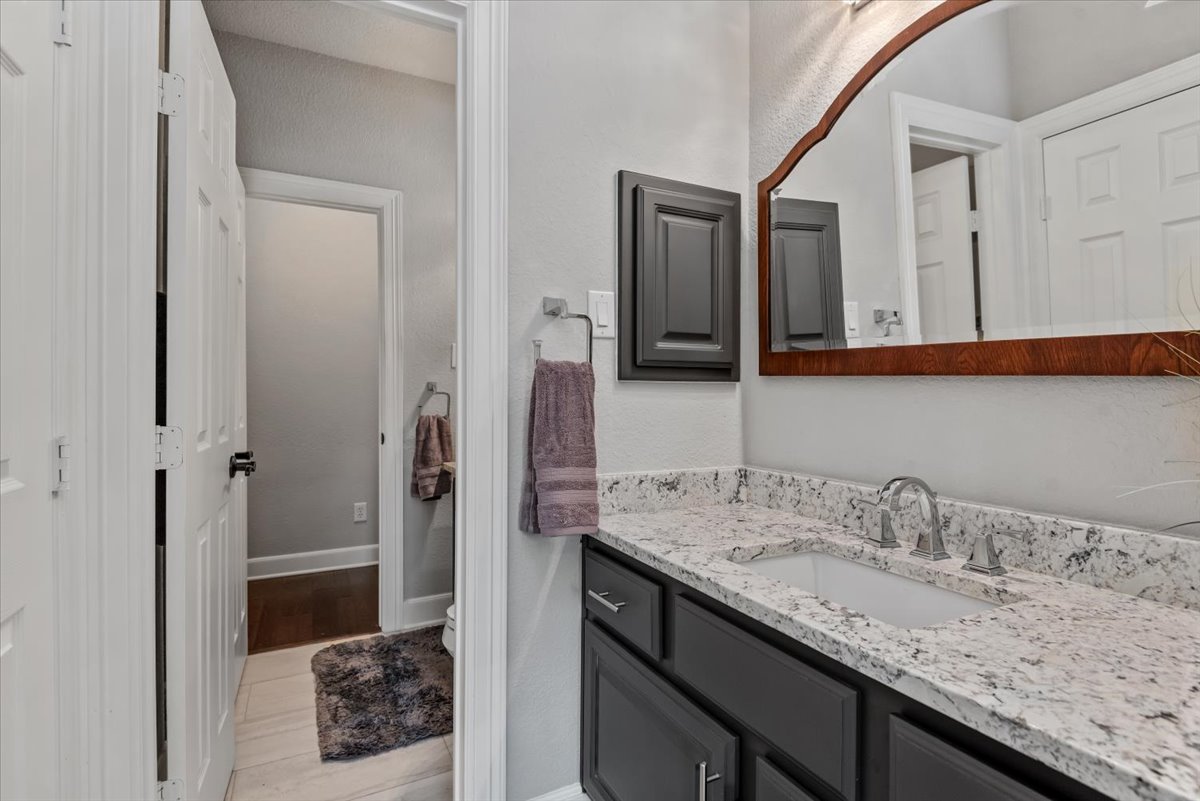 15519 Stallion Point Circle Cypress, TX 77429 - Photo 20 of 37 The bathroom features a vanity with a white granite countertop and a rectangular sink, complemented by a large mirror with a wooden frame