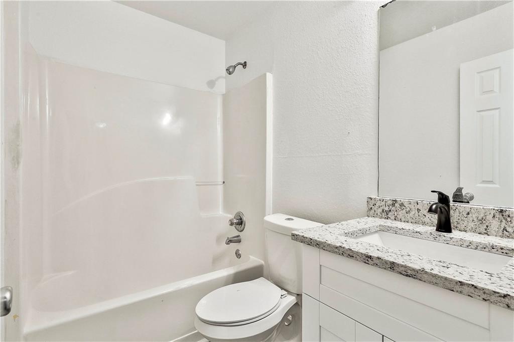 4605 Raven Wood Loop Union City, GA 30291 - Photo 19 of 24 a bathroom with a granite countertop sink a toilet a mirror and bathtub
