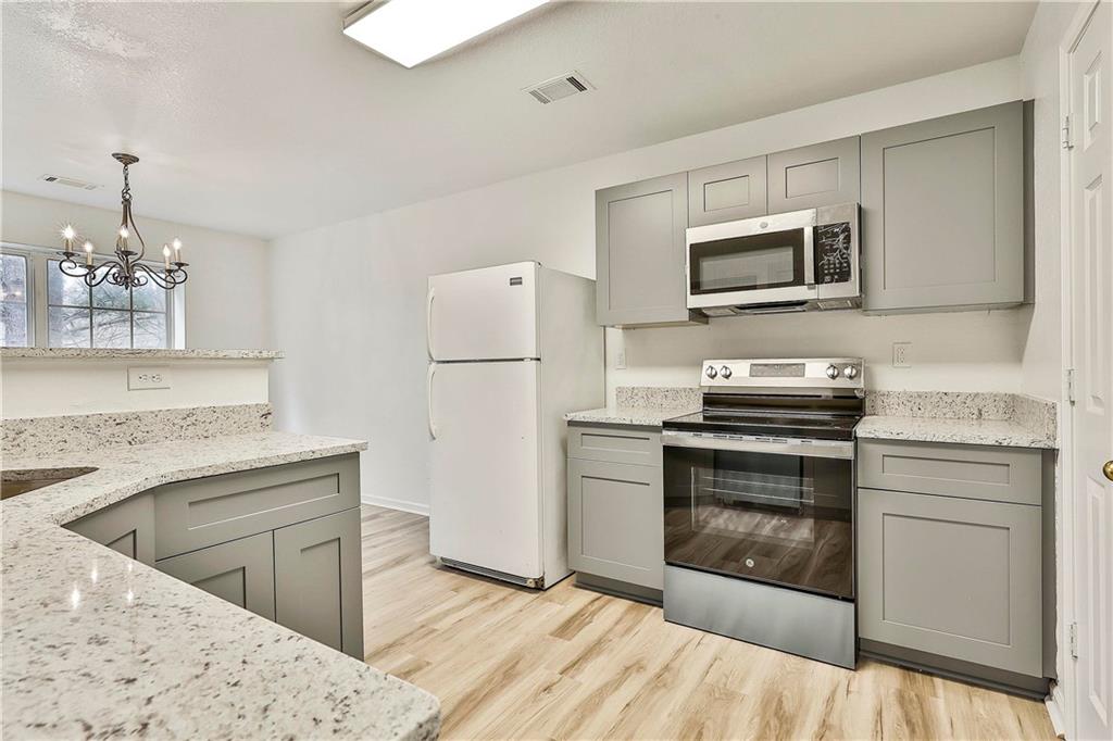 4605 Raven Wood Loop Union City, GA 30291 - Photo 8 of 24 a kitchen with stainless steel appliances kitchen island granite countertop a stove top oven a sink dishwasher and a refrigerator with wooden floor