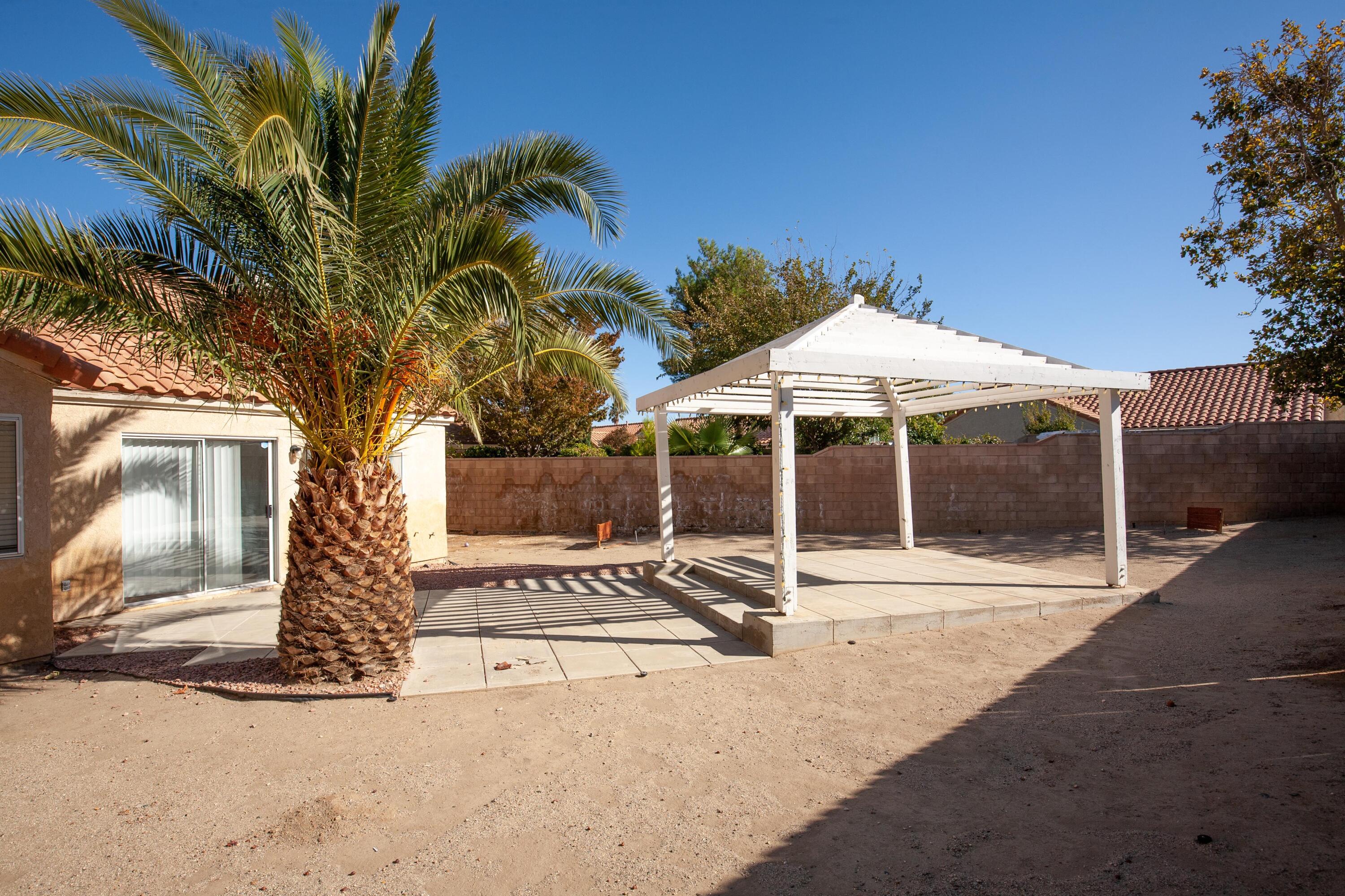 1628 Kings Road Palmdale, CA 93551 - Photo 20 of 22 a patio with a table and chairs under an umbrella
