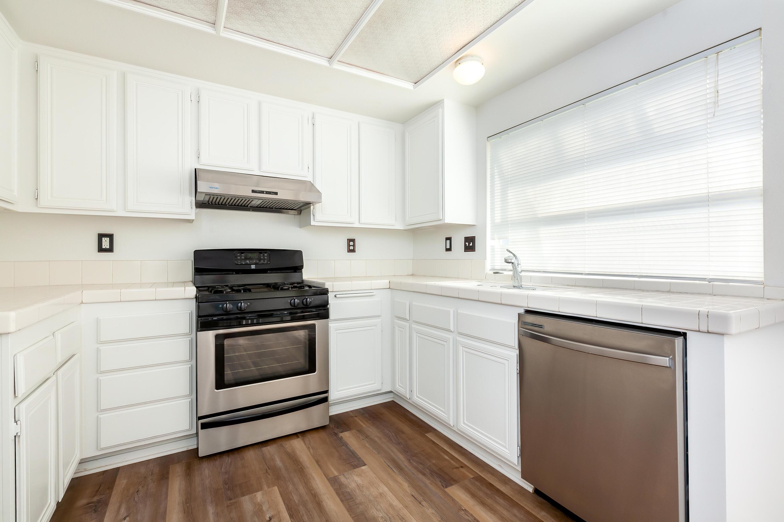 1628 Kings Road Palmdale, CA 93551 - Photo 8 of 22 a kitchen with stainless steel appliances granite countertop a sink and cabinets with wooden floor