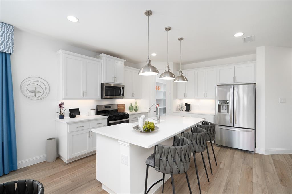 117 Pintail Lane Rhome, TX 76078 - Photo 6 of 29 a kitchen with stainless steel appliances granite countertop a sink a stove a refrigerator and white cabinets with wooden floor