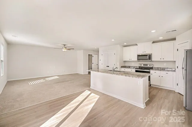 a kitchen with granite countertop a refrigerator and white cabinets