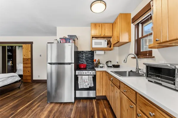 a kitchen with stainless steel appliances granite countertop a refrigerator a sink dishwasher a stove and a dining table with wooden floor