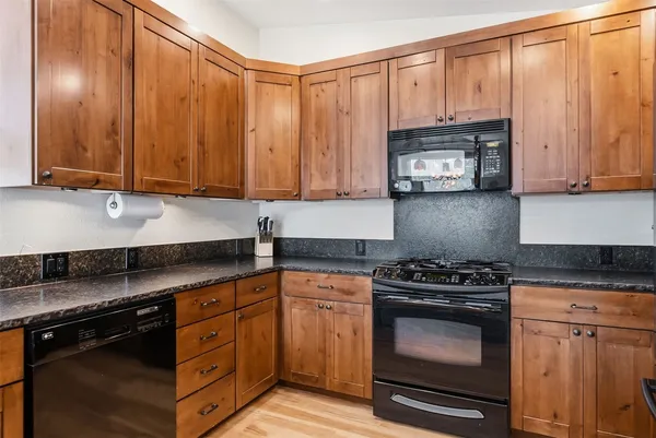 a kitchen with granite countertop wooden cabinets and a stove top oven