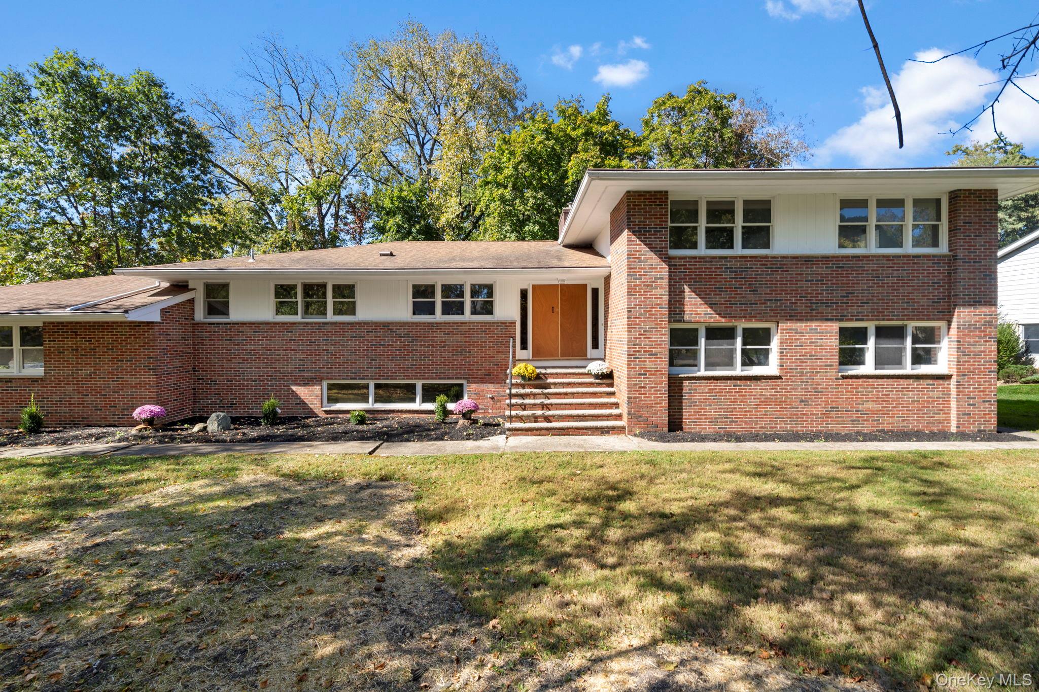 Tri-level home featuring brick siding and a front lawn