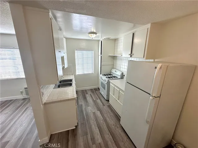 a kitchen with sink refrigerator and wooden floor