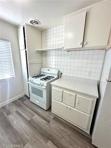 a kitchen with white cabinets stove and sink