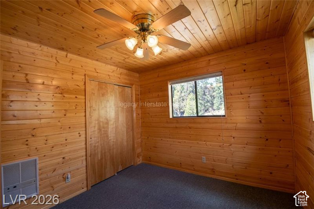 1129 Ponderosa Road, Unit 40 Hatch, UT 84735 - Photo 27 of 47 Wood-paneled walls and ceiling, ceiling fan with integrated lighting, window with exterior scenery, wood-finish closet doors, and carpet flooring