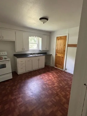 a kitchen with granite countertop a sink stove and cabinets