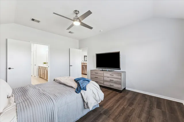 a bedroom with a bed a flat screen tv and a chandelier