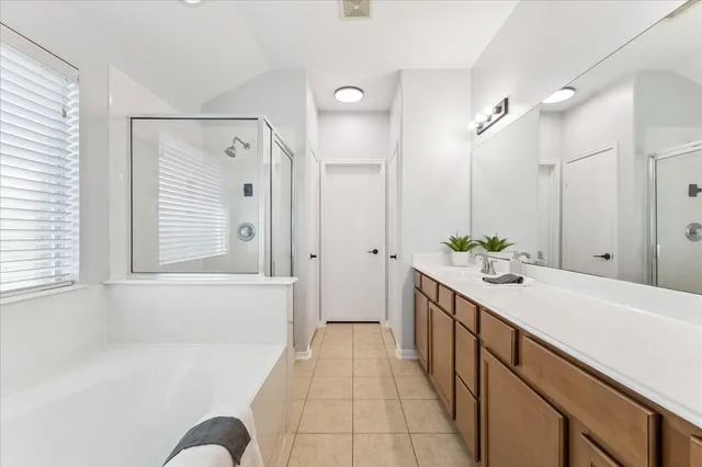a spacious bathroom with a tub sink and mirror