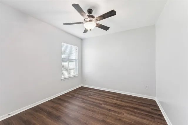 an empty room with wooden floor and ceiling fan