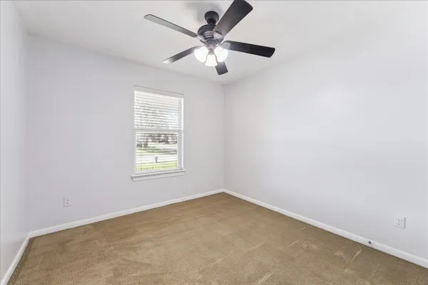 an empty room with a window and a fan