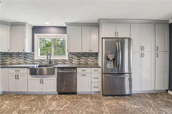 a kitchen with granite countertop a refrigerator and a sink