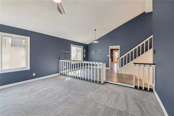 a view of an empty room with stairs & windows