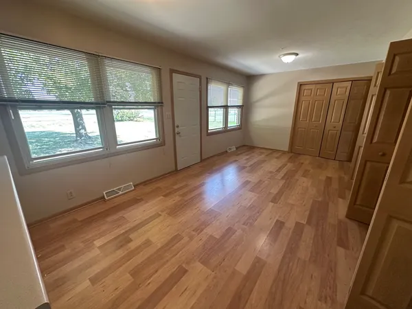 a view of an empty room with wooden floor and a window