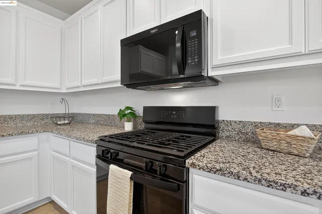 a kitchen with stainless steel appliances granite countertop white cabinets and a stove top oven