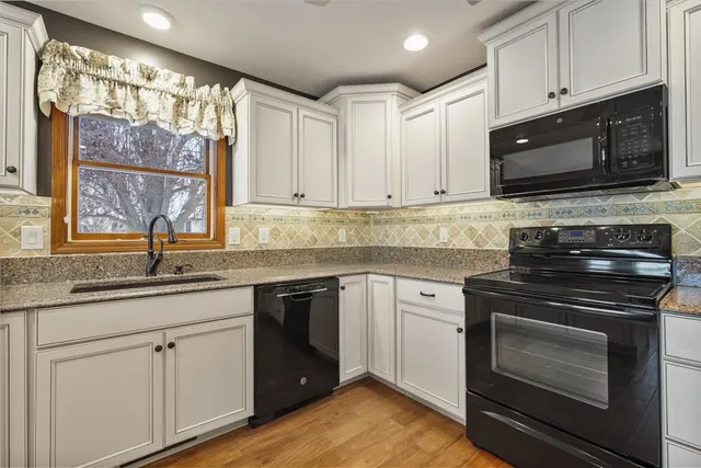 a kitchen with granite countertop white cabinets stainless steel appliances and a sink