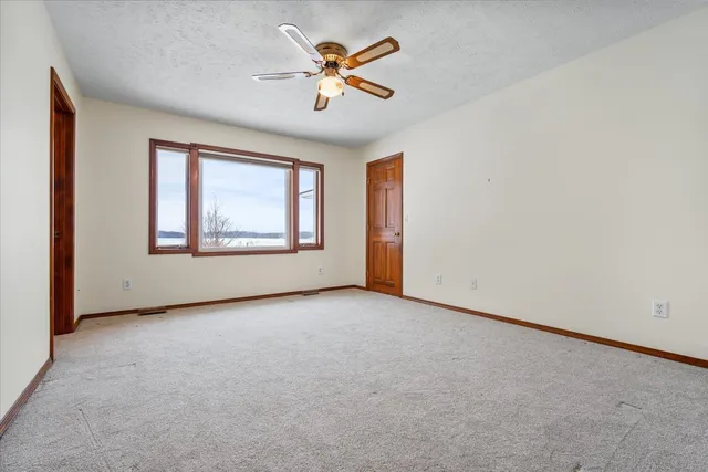 an empty room with windows and ceiling fan