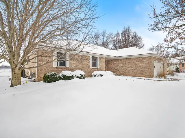 a front view of a house with a yard covered in snow