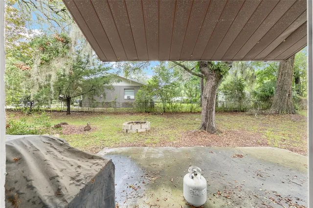 a view of a backyard with table and chairs potted plants and palm tree