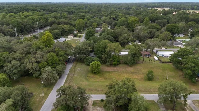 an aerial view of residential houses with outdoor space and trees