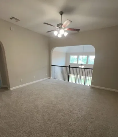 a view of an empty room with chandelier fan