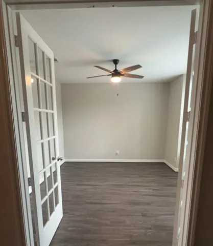 a view of an empty room with wooden floor and a window
