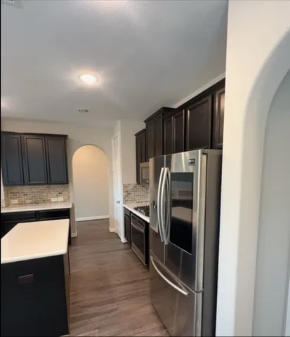 a kitchen with granite countertop a refrigerator and a stove top oven