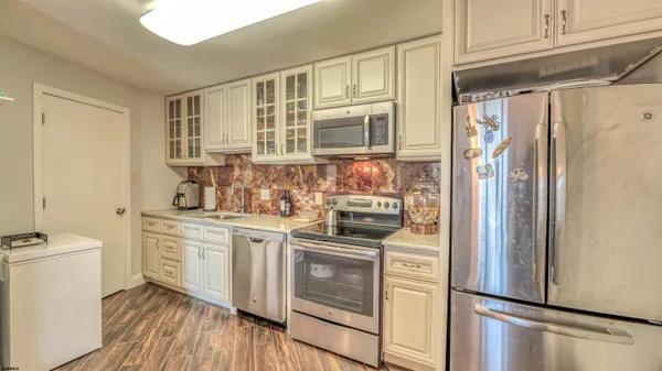 a kitchen with stainless steel appliances a refrigerator a stove and white cabinets