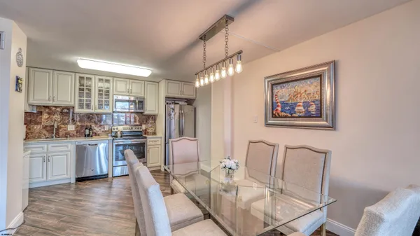 a kitchen with stainless steel appliances granite countertop a stove top oven a sink a dining table and chairs with wooden floor