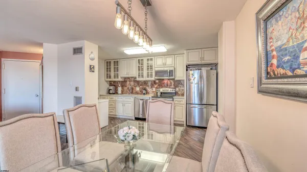 a kitchen with stainless steel appliances a refrigerator a stove a sink dishwasher and white cabinets with wooden floor