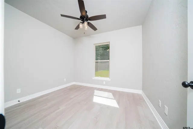 an empty room with a window and a fan