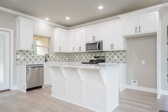 a kitchen with kitchen island granite countertop white cabinets and stainless steel appliances